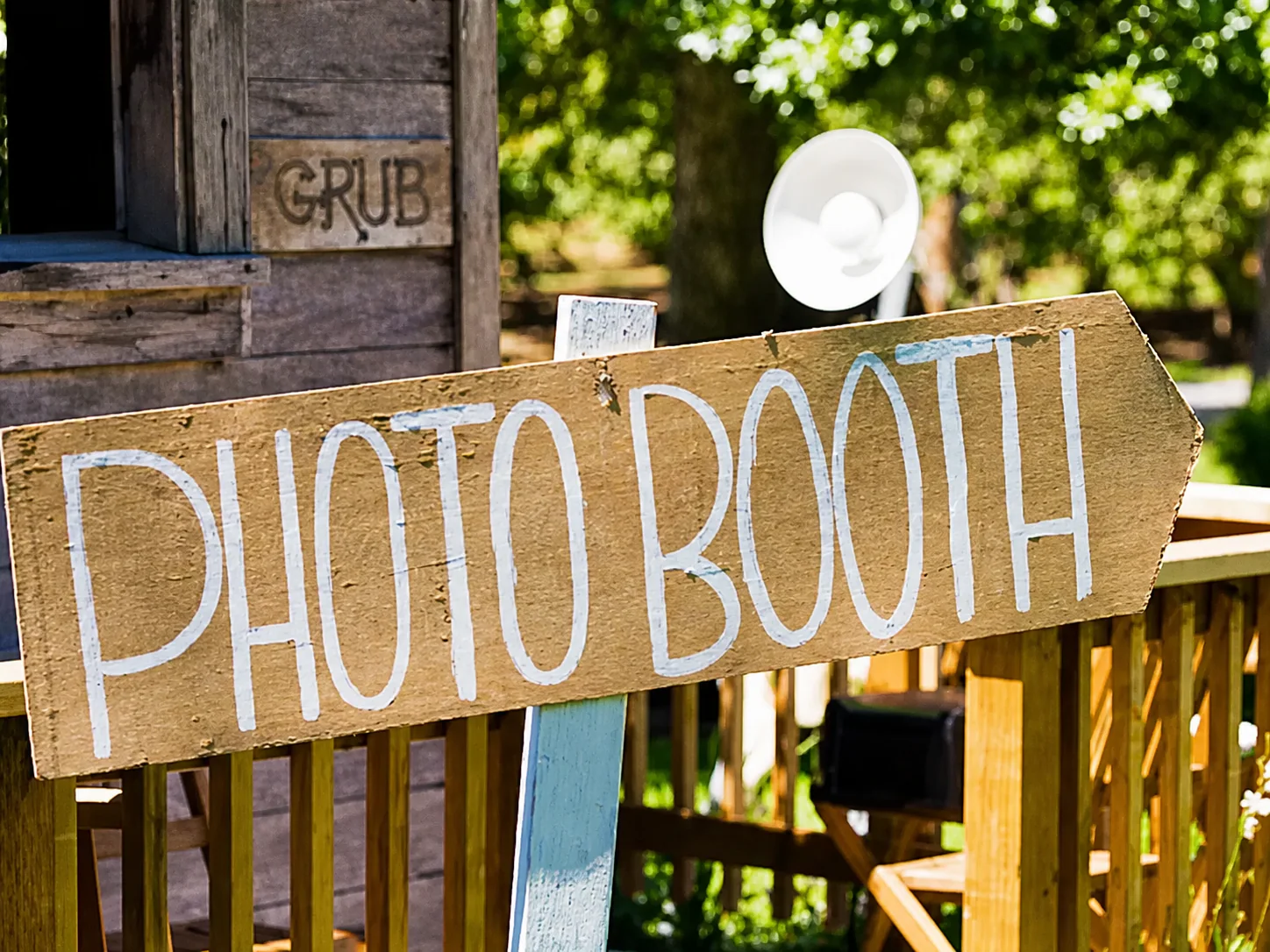 Un panneau en bois peint à la main indiquant « Photo booth » sur une terrasse en extérieur.